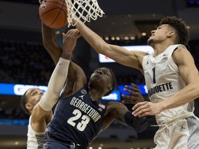 Georgetown forward Josh LeBlanc, center, battles for the rebound against Marquette forward Theo John, left, and forward Brendan Bailey, right, during the first half of an NCAA college basketball game Saturday, March 9, 2019, in Milwaukee.