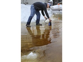Matt Bue pumps water from his alley to the street in Eau Claire, Wis., on Wednesday, March 13, 2019. The high water was filling his garage along Vine Street. Rain and melting snow have triggered flood warnings in some Upper Midwestern states while blizzard conditions are the primary concern in other states.