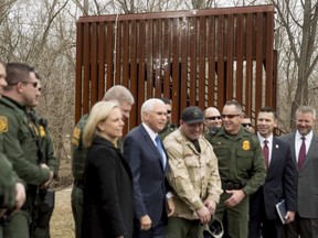 A section of a border wall used for training is visible behind Vice President Mike Pence, center, as he poses for a photograph with Border Patrol agents following a border wall training demonstration at the U.S. Customs and Border Protection Advanced Training Facility in Harpers Ferry, W.Va. Wednesday, March 13, 2019.