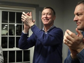 FILE - In this Feb. 13, 2019, file photo, former Colorado Gov. John Hickenlooper, left, applauds at a campaign house party in Manchester, N.H. While the Democratic primary field has shifted left, polls show registered Democratic voters just want someone who can beat Donald Trump. That's led to a potential contradiction being worked over by primary voters. Is the best route to victory to build a liberal movement to win converts or choose a more moderate candidate who can appeal to swing voters?