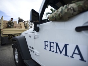 FILE - In this Oct. 5, 2017 file photo, Department of Homeland Security personnel deliver supplies to Santa Ana community residents in the aftermath of Hurricane Maria in Guayama, Puerto Rico. A government watchdog has found the Federal Emergency Management Agency wrongly released to a contractor the personal information of 2.3 million survivors of hurricanes Harvey, Irma and Maria and the California wildfires in 2017.