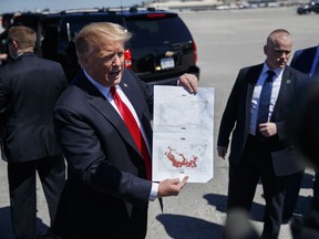 FILE - In this March 22, 2019, photo, President Donald Trump holds a a copy of two maps of Syria as he arrives on Air Force One, Friday, March 22, 2019, at Palm Beach International Airport, in West Palm Beach, Fla. There was just one problem when Trump walked down the stairs of Air Force One and unceremoniously declared that the Islamic State had lost the last of its territory in Syria. He wasn't supposed to announce it yet.