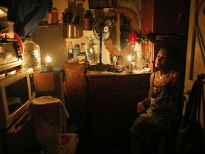 72-year-old Elizabeth Guzman Espitia sits in her windowless room during a blackout in the Santa Cruz of the East neighborhood, in Caracas, Venezuela, Thursday, March 14, 2019. Power has surged back to life across most of Venezuela ending the worst blackout in the crisis-wracked nation's modern history. But Santa Cruz of the East residents don't know when they'll have lights again.