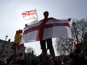 A Brexit supporter holds an England flag at Parliament Square in Westminster, London, Friday, March 29, 2019. Pro-Brexit demonstrators were gathering in central London on the day that Britain was originally scheduled to leave the European Union. British lawmakers will vote Friday on what Prime Minister Theresa May's government described as the "last chance to vote for Brexit."