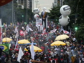 People gather, some holding a inflatable doll with the image of Brazil's president Jair Bolsonaro, during a protest against the pension reforms proposed by his government in Sao Paulo, Brazil, Friday, March 22, 2019.