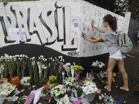 A student places her handprints on a wall at the Raul Brasil State School one day after a mass shooting, in Suzano, Brazil, Thursday, March 14, 2019. Classmates, friends and families began saying goodbye on Thursday, with thousands attending a wake in the Sao Paulo suburb while authorities worked to understand what drove two former students to attack the school with a gun, crossbows and small axes.