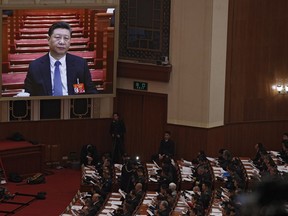 Chinese President Xi Jinping is seen on a big screen as his Premier Li Keqiang delivers the work report at the opening session of the annual National People's Congress at the Great Hall of the People in Beijing, Tuesday, March 5, 2019. China's government announced a robust annual economic growth target and a 7.5 percent rise in military spending Tuesday at a legislative session overshadowed by a tariff war with Washington.