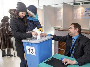 An election commission employee helps a woman with her child to cast a ballot at a polling station during a parliamentary elections in Tallinn, Estonia, Sunday, March 3, 2019. Estonians are voting in a parliamentary election Sunday in the small Baltic nation in a ballot where Prime Minister Juri Ratas and his Center Party are pitted against the center-right opposition Reform Party and where populists are seen making inroads.