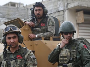 FILE - In this March 24, 2018 file photo, Turkish soldiers atop an armored personnel carrier secure the streets of the northwestern city of Afrin, Syria, during a Turkish government-organized media tour into northern Syria. Turkish military said Sunday, March. 31, 2019 that one of its soldier has been killed in Syria's north in what Syrian activists describe as an attack by local Kurdish fighters. Turkey's ministry of defense said a mortar attack Sunday on its troops around Afrin in northwestern Syria killed one soldier and wounded another.