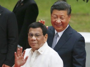 FILE - In this Nov. 20, 2018, file photo, Chinese President Xi Jinping and Philippine President Rodrigo Duterte wave to the media following the welcome ceremony at Malacanang Palace in Manila, Philippines. Two former Philippine officials have filed a complaint with the International Criminal Court accusing Chinese President Xi Jinping of crimes against humanity over his government's assertive actions in the disputed South China Sea, which they say deprived thousands of fishermen of their livelihoods and destroyed the environment.
