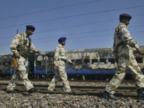 FILE - In this  Feb. 19, 2007, file photo, Indian security personnel walk past the charred coaches of Samjauta Express train, or Friendship Express, which caught fire after a blast at Dewana, about 80 kilometers (50 miles) north of New Delhi, India. An Indian court has on Wednesday, March 20, 2019, acquitted four Hindu hardliners charged with triggering explosions in the train heading for India's border with Pakistan 12 years ago, killing 68 people, mostly Pakistani nationals.