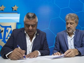General Secretary of the Argentina's Footballers' Union (FAA) Sergio Marchi, right, Claudio Tapia, president of Argentina's Soccer Federation, left, sign the contract to implement a plan to professionalize women's soccer in Buenos Aires, Argentina, Saturday, March 16, 2019. Almost 90 years after men's soccer turned professional in Argentina, the women's game is still being played by amateur athletes who get little to no money for their work on the field.