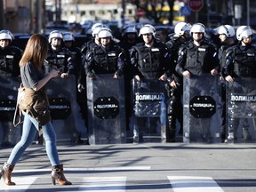 A woman walks in front of a police cordon in front of the Belgrade police headquarters in Belgrade, Serbia, Sunday, March 17, 2019. The opposition clashes with police on Saturday and Sunday in Belgrade, the capital, were the first major incidents after months of peaceful protests against populist President Aleksandar Vucic. The demonstrators are demanding his resignation, fair elections and a free media.
