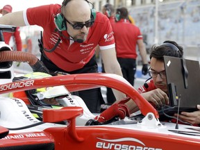 Formula 2 driver Mick Schumacher, left, speaks to mechanics as he prepares for the Formula 2 qualifying session at the Bahrain International Circuit in Sakhir, Bahrain, Friday, March 29, 2019. It promises to be a whirlwind few days for the son of Formula One great Michael Schumacher, as he makes his F2 debut this weekend and then drives in his first F1 test for Ferrari on Tuesday.