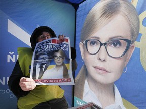 An agitator holds a paper reading "What country will we wake up in?" as she sits inside a campaigning tent of presidential candidate Yulia Tymoshenko, Ukraine's former prime minister, in Kiev, Ukraine, Thursday, March 28 2019. Ukraine will vote for the new president on March 31