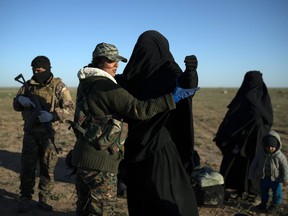 A woman is frisked by a U.S.-backed Syrian Democratic Forces (SDF) fighter at a screening area after being evacuated out of the last territory held by Islamic State militants, in the desert outside Baghouz, Syria, Friday, March 1, 2019.