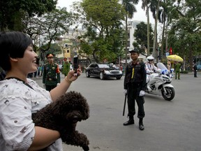 A woman with her pet dog watch as motorcade of North Korean leader Kim Jong Un is driven off Melia hotel in Hanoi, Vietnam, Saturday, March 2, 2019.