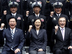FILE - In this March 21, 2017, file photo, Taiwan's President Tsai Ing-wen, center, along with Defense Minister Feng Shih-kuan, right, and Secretary-General of National Security Council Joseph Wu, left, cheer with navy officers during a visit to Zuoying Naval base in Kaohsiung, southern Taiwan. China says attempts by Taiwan's government to block its goal of bringing the self-governing island under Beijing's control are like "stretching out an arm to block a car." The new rhetorical broadside was launched late Tuesday, March 12, 2019 against Taiwanese President Tsai following her announcement of guidelines to counter China's "one country, two systems" framework for political unification with the island.