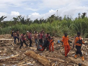 CORRECTS YEAR - In this photo provided by National Search and Rescue Agency (BASARNAS), the agency's personnel and police carry the body of flood victim at Sentani, Papua Province, Indonesia, Sunday, March 17, 2019. Flash flood and mudslides triggered by days of torrential downpours tore through mountainside villages in Indonesia's easternmost province, killing dozens of people, disaster officials said Sunday. (BASARNAS via AP)