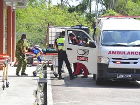 Emergency personnel unload a student from an ambulance after toxic chemical spill in Pasir Gudang, Johor state, on Wednesday, March 13, 2019. Malaysia's education ministry has ordered 34 schools to be closed in southern Johor state after toxic waste believed dumped in a river sickened dozens of students and teachers.