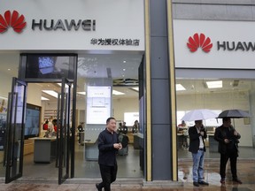 People walk past a Huawei retail shop in Shenzhen, China's Guangdong province, Thursday, March 7, 2019. Chinese tech giant Huawei is challenging a U.S. law that labels the company a security risk and would limit its access to the American market for telecom equipment.