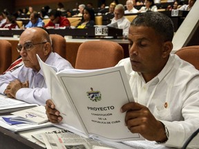 FILE - In this July 21, 2018 photo, a member of the National Assembly studies the proposed constitutional update in Havana, Cuba. Some observers see the new constitution as a merely cosmetic update aimed at assuring one of the world's last communist systems won't get another revamp until long after the passing of its founding fathers, while others see the potential for a slow-moving but deep set of changes that will speed the modernization of Cuba's economically stagnant authoritarian bureaucracy.