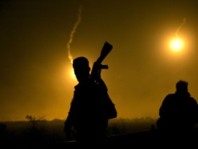 A U.S.-backed Syrian Democratic Forces (SDF) fighter watches illumination rounds light up Baghouz, Syria, as the last pocket of Islamic State militants is attacked on Tuesday, March 12, 2019.