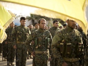 U.S.-backed Syrian Democratic Forces (SDF) stand in formation at a ceremony to mark their defeat of Islamic State militants in Baghouz, at al-Omar Oil Field base, Syria, Saturday, March 23, 2019.