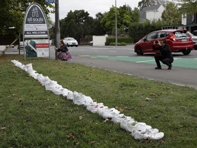 People photograph a memorial of 50 pairs of whites shoes for the victims of Friday March 15 mass mosque shootings in front of a church in Christchurch, New Zealand, Tuesday, March 19, 2019.  Four days after Friday's attack, New Zealand's deadliest shooting in modern history, relatives were anxiously waiting for word on when they can bury their loved ones.