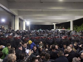 Protesters sit in front of a riot police cordon at an entrance to the state-run TV headquarters in Belgrade, Serbia, Saturday, March 16, 2019. Demonstrators protesting the autocratic rule of Serbian President Aleksandar Vucic burst into the state-run TV headquarters in Belgrade on Saturday to denounce a broadcaster whose reporting they consider highly biased.