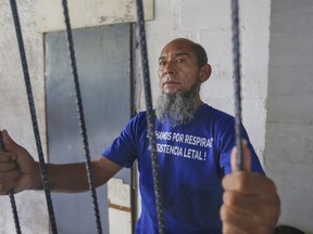 Alex Vanegas holds on to the iron bars he had installed on the porch of his apartment to symbolize his home arrest in Managua, Nicaragua, Tuesday, March 5, 2019. Grasping the iron bars, Vanegas is taken back to the dark prison cells where he spent the previous four months talking to fellow inmates through holes in the walls that also let in rats, scorpions and cockroaches, arrested for protesting against the government of President Daniel Ortega.
