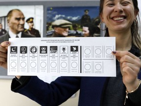 An official female shows the ballot voting paper with names and the parties a polling station during the municipal elections in Ankara, Turkey, Sunday, March 31, 2019. Turkish citizens have begun casting votes in municipal elections for mayors, local assembly representatives and neighborhood or village administrators that are seen as a barometer of Erdogan's popularity amid a sharp economic downturn.