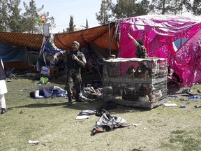 Police and civilians lie on the ground after multiple explosions in Lashkar Gah city of Helmand province, southern Afghanistan, Saturday, Mar. 23, 2019. An Afghan official says that at least three have been killed in twin bomb explosions occurred during the Farmer's Day ceremony in southern Helmand province.