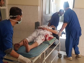 Hospital staff members carry a wounded victim on stretcher to emergency ward in Kabul, Afghanistan, Thursday, March 21, 2019. An Afghan official says three explosions have struck near a Shiite shrine and cemetery in western Kabul as people gathered there to mark the holiday of Nowruz, the Persian New Year.
