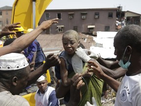 A child is rescued from the rubble of a collapsed building in Lagos, Nigeria, Wednesday March 13, 2019. Rescue efforts are underway in Nigeria after a three-storey school building collapsed while classes were in session, with some scores of children thought to be inside at the time.