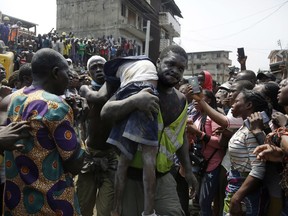 A body of a child is recovered from the rubble of a collapsed building in Lagos, Nigeria, Wednesday March 13, 2019. Rescue efforts are underway in Nigeria after a three-storey school building collapsed while classes were in session, with some scores of children thought to be inside at the time.