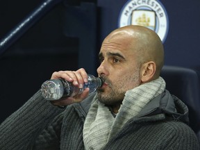 Manchester City coach Pep Guardiola drinks a water as he waits for the start of the Champions League round of 16 second leg, soccer match between Manchester City and Schalke 04 at Etihad stadium in Manchester, England, Tuesday, March 12, 2019.