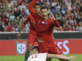 Serbia's Nikola Milenkovic, bottom, and Portugal's Cristiano Ronaldo challenge for the ball during the Euro 2020 group B qualifying soccer match between Portugal and Serbia at the Luz stadium in Lisbon, Portugal, Monday, March 25, 2019.