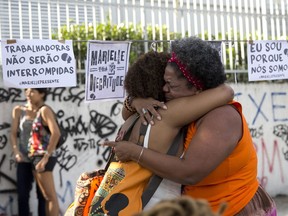 Women embrace at the site where Rio councilwoman Marielle Franco was gunned down, during a demonstration marking the one year anniversary of her death, in Rio de Janeiro, Brazil, Thursday, March 14, 2019.  Authorities arrested two former police officers Tuesday in the killing of Franco and her driver Anderson Gomes, a brazen assassination that shocked Brazilians and sparked protests in several countries.