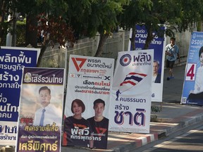 In this March 12, 2019, photo, a pedestrian walks past the election campaign posters in Bangkok, Thailand. Thailand heads to the polls Sunday, March 24, 2019 to vote in the country's first general election since the military toppled an elected government in a coup nearly five years ago.