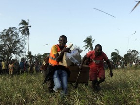 Community members assist a doctor carrying boxes with medical supplies as he runs towards the South African Defence Forces helicopter after assisting a community affected by a cyclone near Beira, Mozambique, Thursday, March 28, 2019. The first cases of cholera have been confirmed in the cyclone-ravaged city of Beira, Mozambican authorities announced on Wednesday, raising the stakes in an already desperate fight to help hundreds of thousands of people sheltering in increasingly squalid conditions.