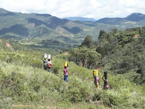 A group of women carry buckets of water to use at a funeral near the area visited by Zimbabwean President Emmerson Mnangagwa, in Chimanimani, about 600 km south east of Harare, Zimbabwe, Wednesday March 20, 2019. Mnangagwa visited a part of Chimanimnani affected by cyclone Idai and promised assitance in the form of food and rebuilding of homes. Hundreds are dead, many more missing and thousands at risk from massive flooding in Mozambique, Malawi and Zimbabwe caused by Cyclone Idai.