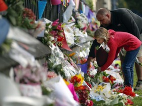 Mourners lays flowers on a wall at the Botanical Gardens in Christchurch, New Zealand, Saturday, March 16, 2019. New Zealand's stricken residents reached out to Muslims in their neighborhoods and around the country on Saturday, in a fierce determination to show kindness to a community in pain as a 28-year-old white supremacist stood silently before a judge, accused in mass shootings at two mosques that left dozens of people dead.