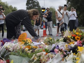 Mourners paying their respects at a makeshift memorial near the Masjid Al Noor mosque, Saturday, March 16, 2019, Christchurch, New Zealand, where one of the two mass shootings occurred. The white supremacist gunman appeared in court Saturday charged with murder in the mosque assaults that killed at least 49 people and led to the prime minister to call for a tightening of national gun laws.