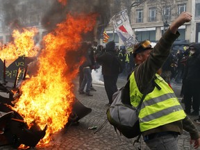 A protester shouts slogans in front of a barricade on fire during a yellow vests demonstration Saturday, March 16, 2019 in Paris. Paris police say more than 100 people have been arrested amid rioting in the French capital by yellow vest protesters and clashes with police. They set life-threatening fires, smashed up luxury stores and clashed with police firing tear gas and water cannon.