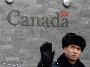 A guard attempts to block photos from being taken outside the Canadian embassy in Beijing on January 27, 2019.