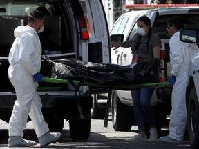 Forensic personnel carry one of the bodies found in a clandestine grave inside a house in Zapopan, State of Jalisco, Mexico, on April 14, 2019.