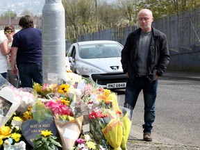 People gather around the floral tributes placed at the scene in Northern Ireland on April 20, 2019 where journalist Lyra McKee was fatally shot amid rioting on April 18.