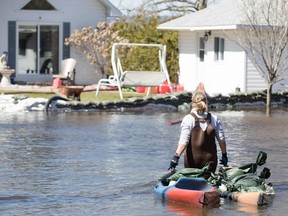 A woman moves sandbags near her house in Constance Bay, west of Ottawa. Spring weather and rains have brought flooding to several areas of Ontario and Quebec.