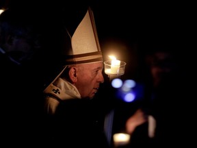 Pope Francis holds a candle as he presides over a solemn Easter vigil ceremony in St. Peter's Basilica at the Vatican, Saturday, April 21, 2019.